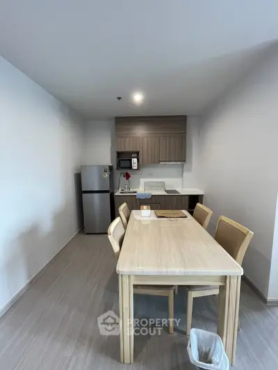 Modern kitchen with wooden dining table and stainless steel fridge in cozy apartment.
