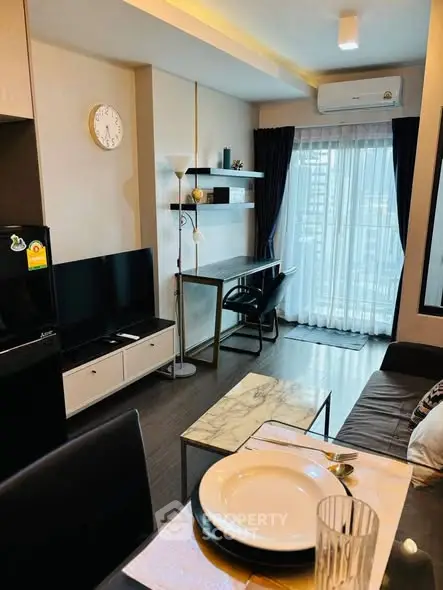 Modern living room with stylish decor and natural light, featuring a sleek TV setup and dining area.