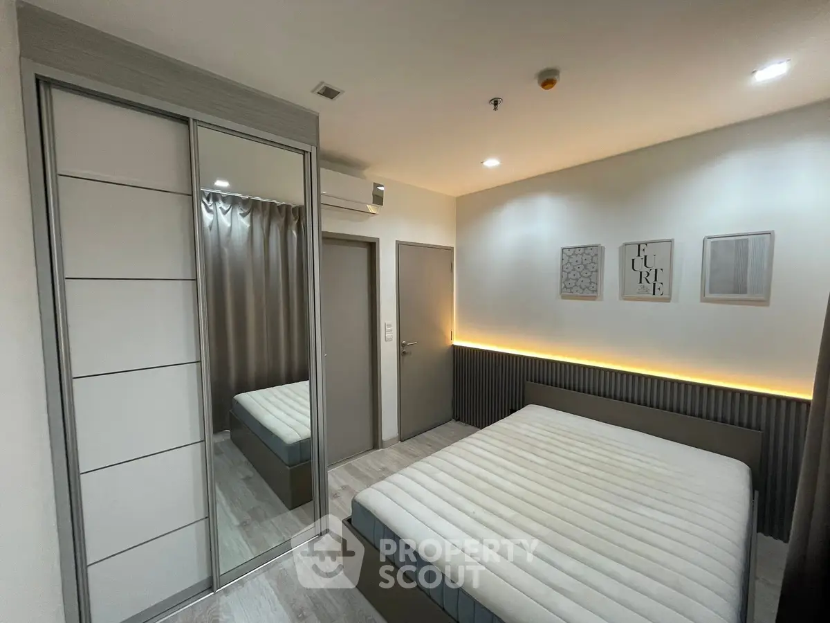 Modern bedroom with sleek design, featuring a large mirror closet and ambient lighting.