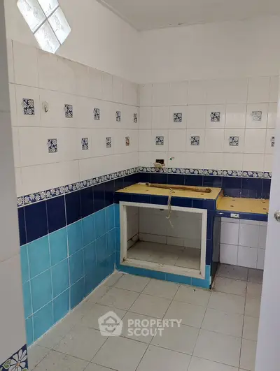 Compact kitchen space with tiled walls and open counter layout.