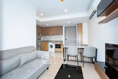 Modern living room with open kitchen, featuring sleek furniture and built-in appliances in a stylish apartment.