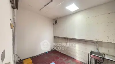 Spacious utility room with sink and tiled floor, ideal for storage or laundry setup.
