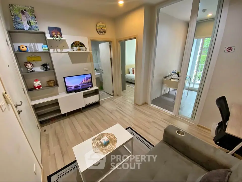 Modern living room with open view to bedroom and study area, featuring sleek furniture and decor.