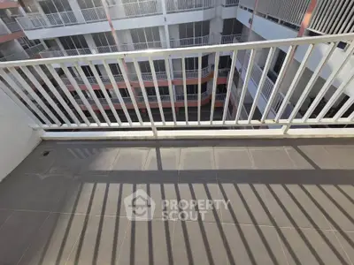 Spacious balcony with modern railing overlooking a multi-story building courtyard.