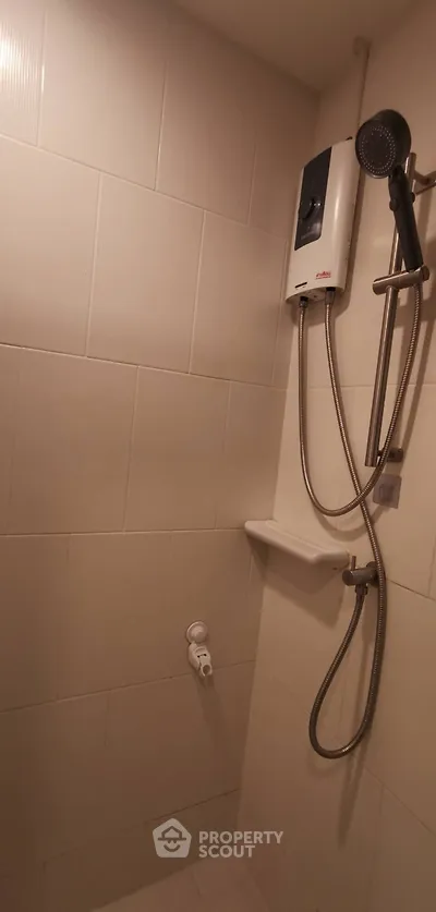 Compact bathroom shower area with water heater and tiled walls.