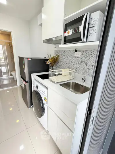 Modern compact kitchen with washing machine and microwave, sleek design and efficient use of space.