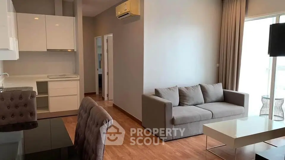 Modern living room with sleek furniture and open kitchen layout in a stylish apartment.