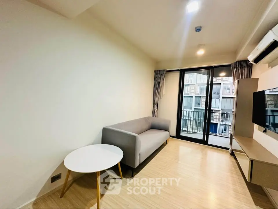 Modern living room with balcony view, featuring sleek furniture and natural light.