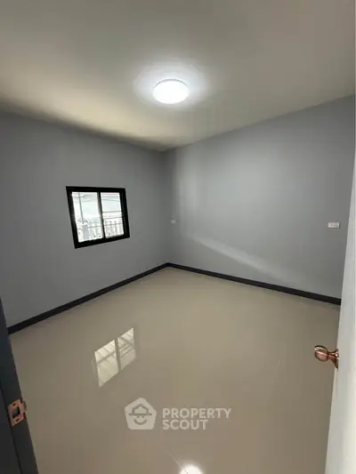 Spacious empty room with glossy tiled floor and window, perfect for customization.