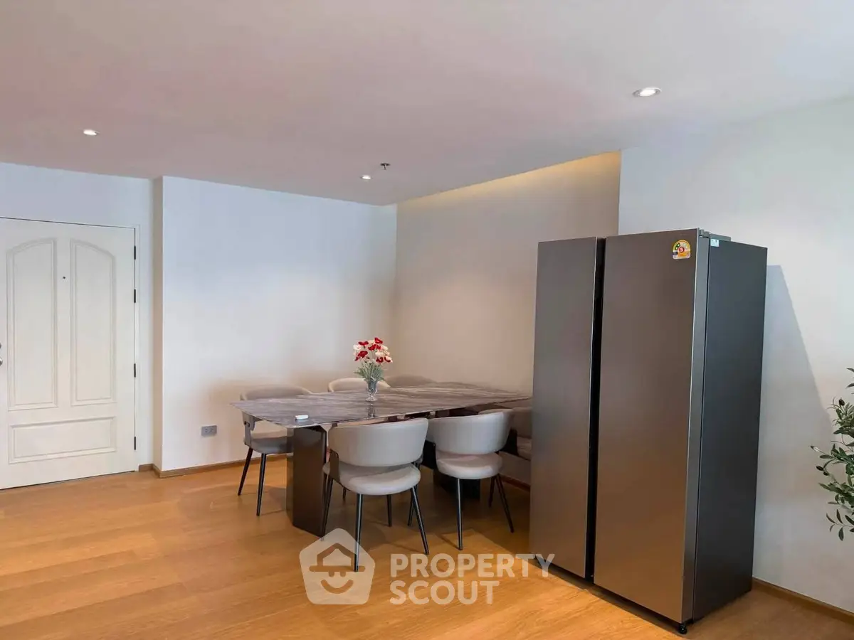 Modern dining area with sleek refrigerator and elegant table setting in a stylish apartment.