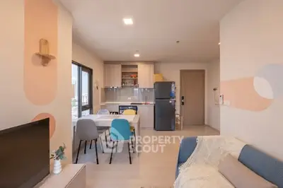 Modern open-plan living room with stylish kitchen and colorful dining chairs.