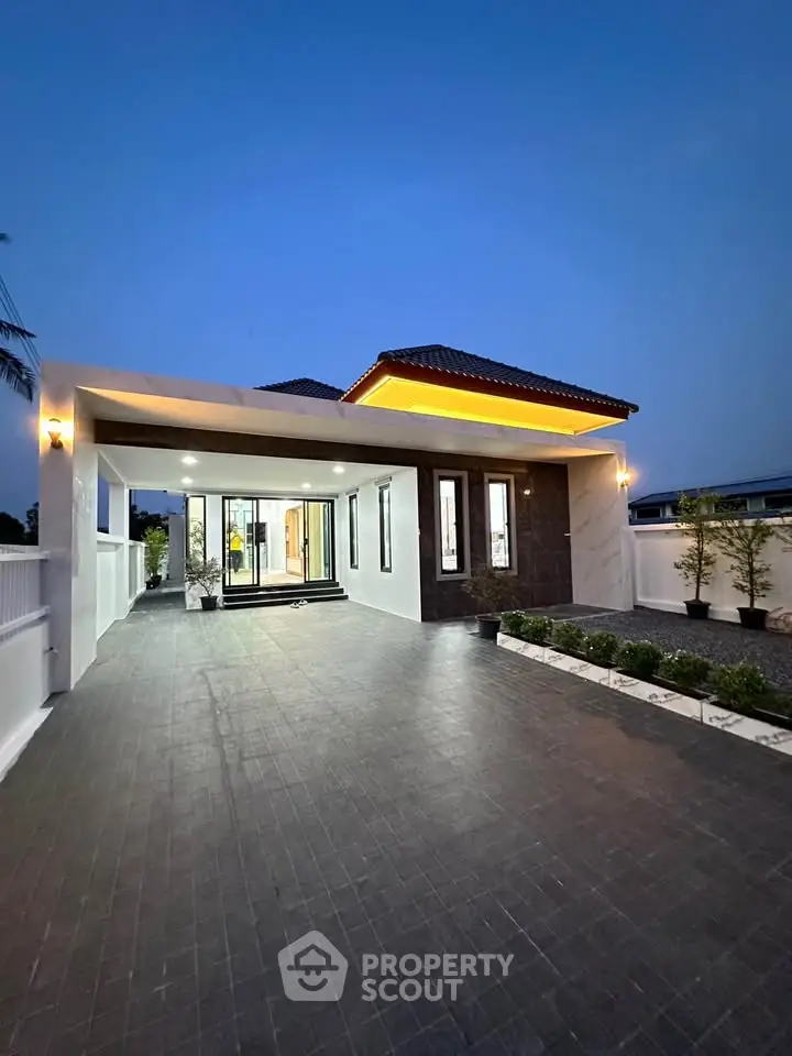 Modern single-story house with elegant exterior lighting and spacious driveway at dusk.
