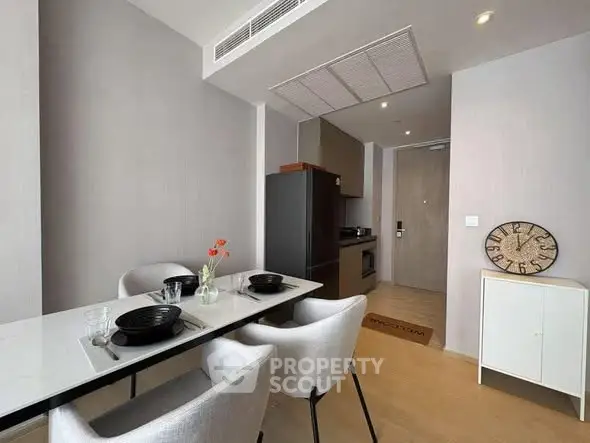Modern dining area with sleek table and chairs, adjacent to a compact kitchen in a stylish apartment.