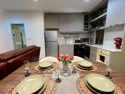Modern kitchen with dining area, featuring sleek appliances and elegant table setting.