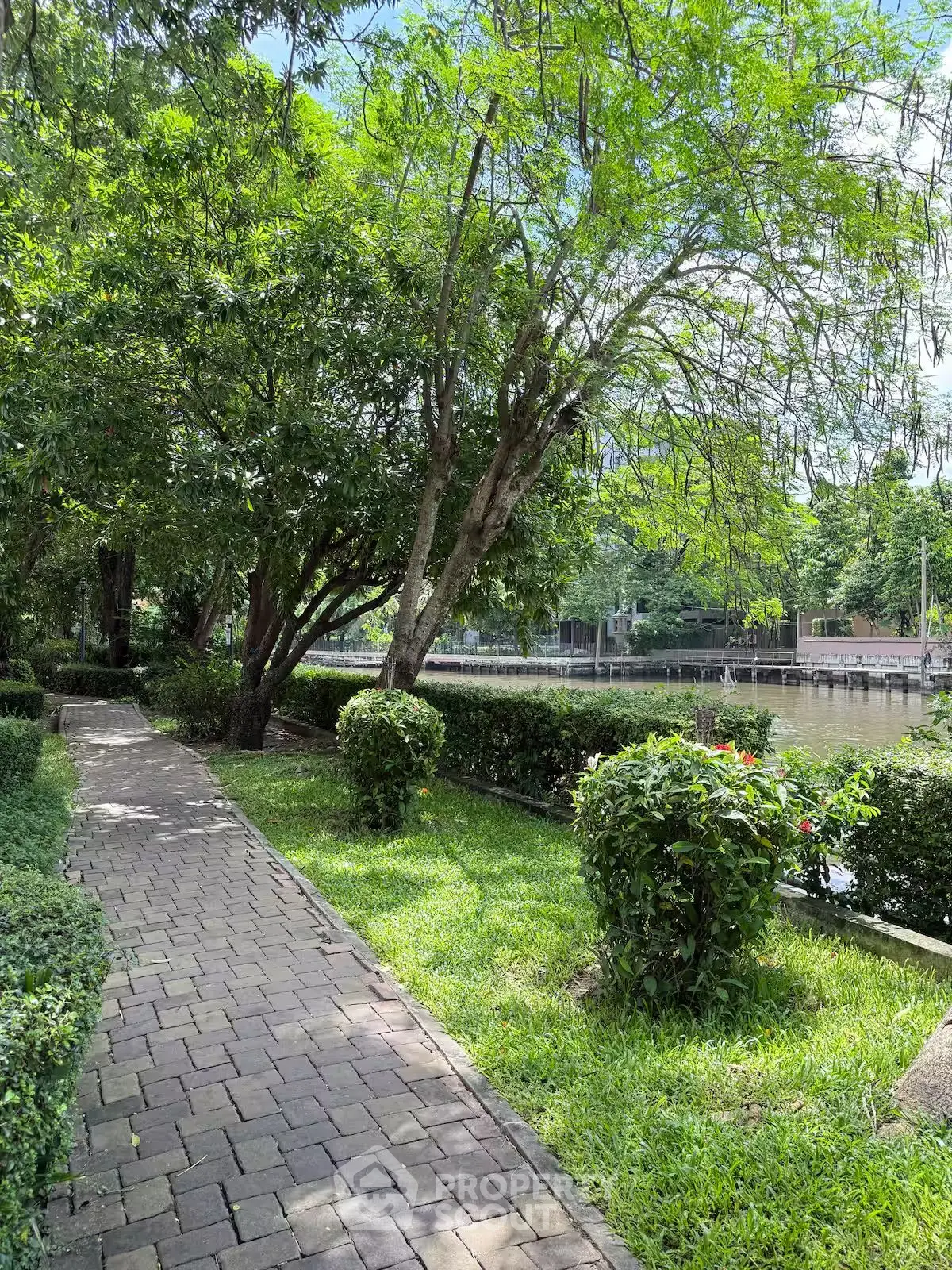 Serene garden pathway with lush greenery and water view, perfect for relaxation.