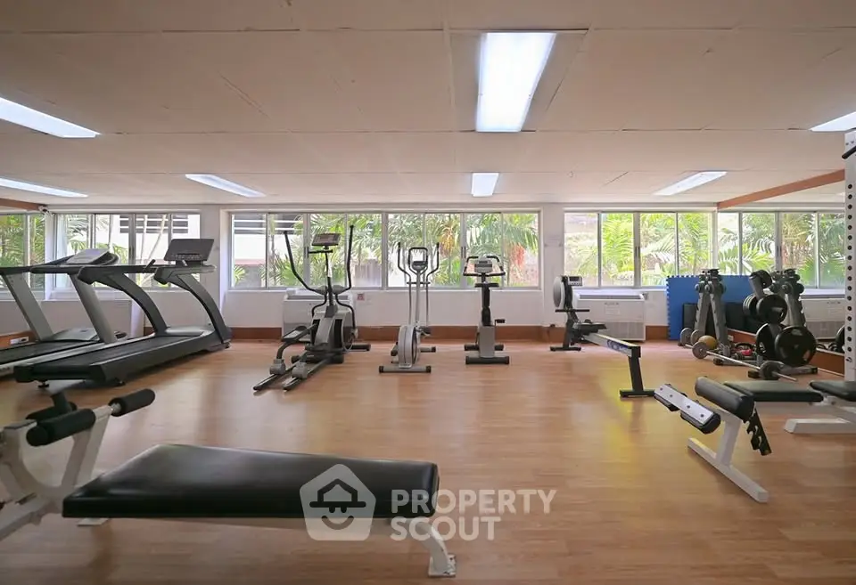 Spacious gym with modern equipment and large windows for natural light.