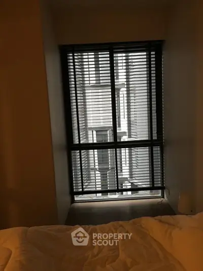 Cozy bedroom with window blinds and urban view