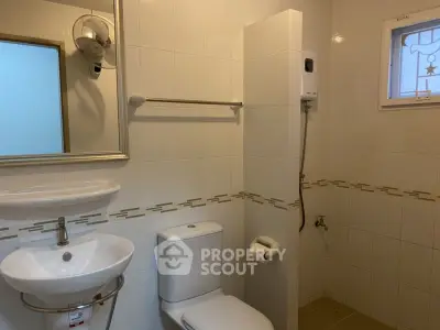 Modern bathroom with sleek fixtures and white tile design, featuring a compact sink and toilet.