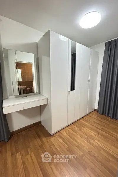 Spacious bedroom with sleek white wardrobe and elegant wooden flooring