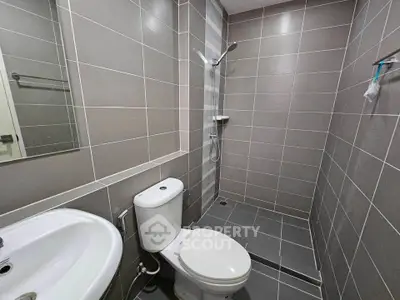 Modern bathroom with sleek tiles and walk-in shower in contemporary apartment.