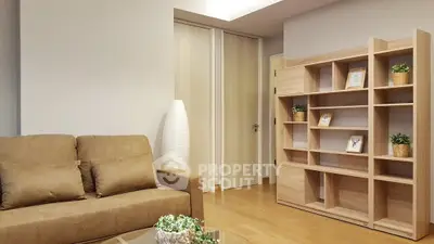 Modern living room with beige sofa and wooden bookshelf, perfect for cozy relaxation.