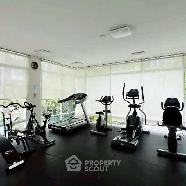 Modern gym with exercise equipment and natural light in a residential building.