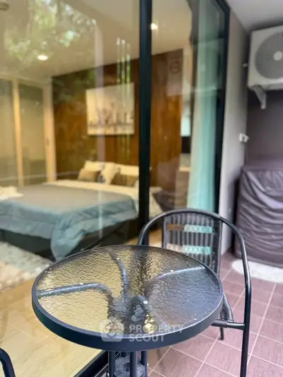Chic balcony view into a modern bedroom with glass table and chairs, perfect for relaxation.