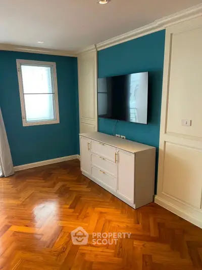 Stylish living room with parquet flooring and mounted TV, featuring elegant blue accent wall.