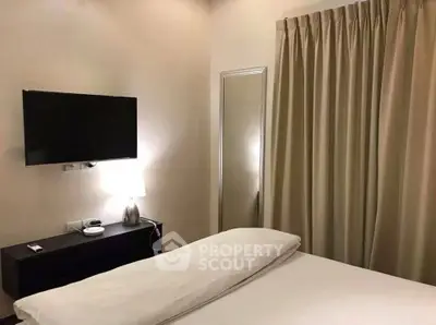 Cozy bedroom with modern TV and elegant curtains, perfect for relaxation.