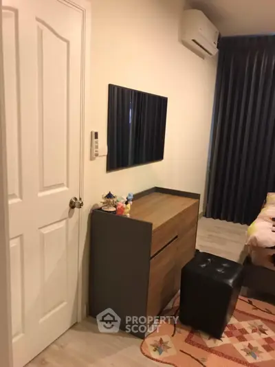 Cozy bedroom with modern decor, featuring a sleek dresser and wall-mounted TV, perfect for relaxation.