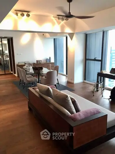 Spacious modern living room with elegant dining area and large windows offering city views.