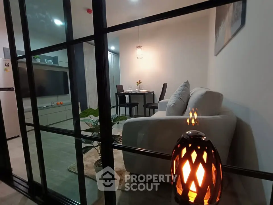 Modern living room with cozy sofa and dining area, featuring elegant lighting and stylish decor.