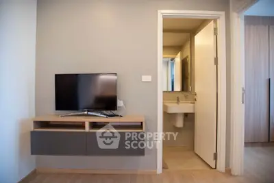 Modern apartment interior with TV and bathroom view, showcasing sleek design and functionality.