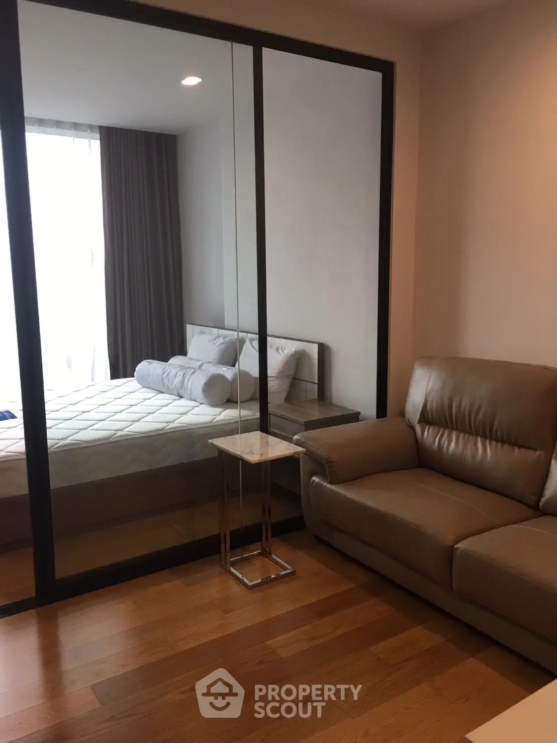 Modern bedroom with glass partition and cozy seating area in a stylish apartment.