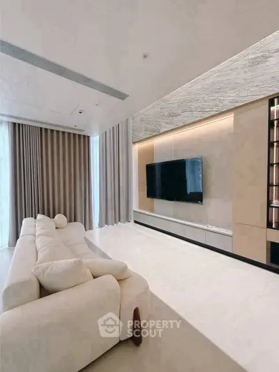Luxurious modern living room with plush sofa and large TV, perfect for relaxation.