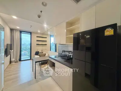 Modern open-plan kitchen and living room with city view and sleek black fridge.