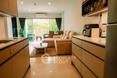 Spacious open-layout kitchen and living room with modern furnishings and large windows offering a lush green view.