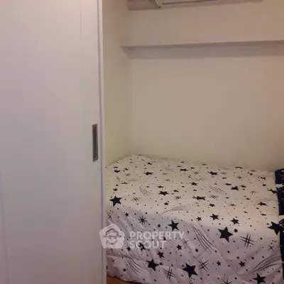 Cozy small bedroom with star-patterned bedding and white wardrobe.