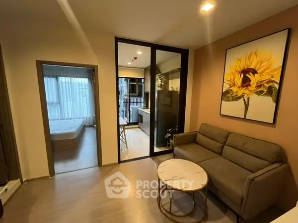 Modern living room with sunflower artwork and view into bedroom and kitchen.