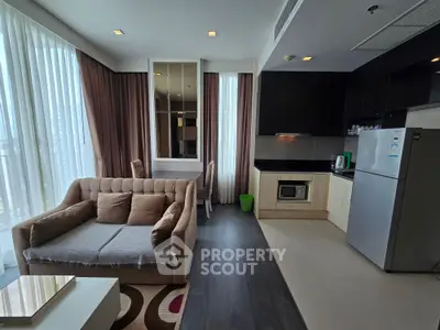 Modern open-layout living room with kitchen, featuring sleek appliances and cozy seating area.