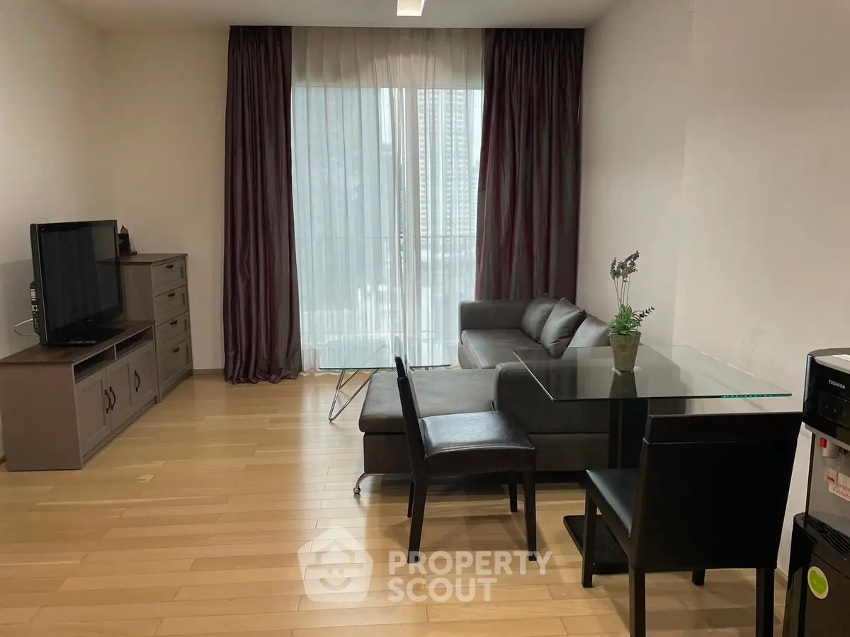 Modern living room with sleek furniture and large window offering natural light.