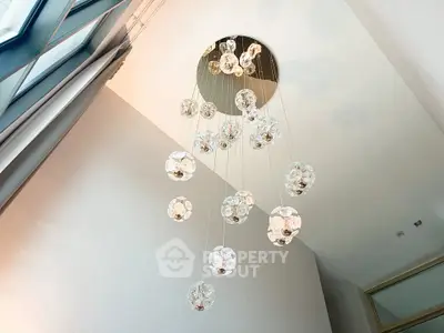 Elegant modern chandelier in a stylish interior space with high ceilings and natural light.
