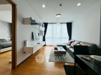 Modern living room with sleek furniture and large window, adjacent to a stylish bedroom.