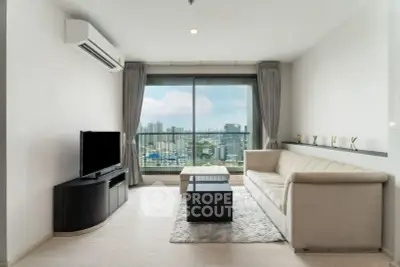 Modern living room with city view, featuring sleek furniture and large window for natural light.