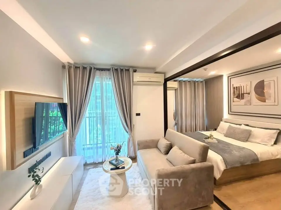 Modern living room with cozy sofa, TV, and elegant bedroom in open layout apartment.