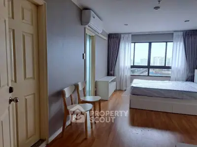 Spacious bedroom with city view, featuring modern furniture and large windows for natural light.