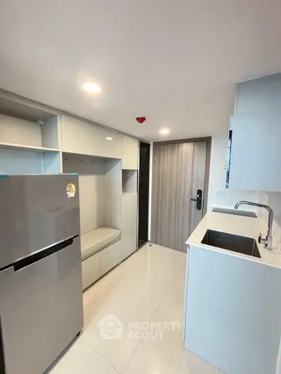 Modern compact kitchen with sleek cabinetry and stainless steel fridge