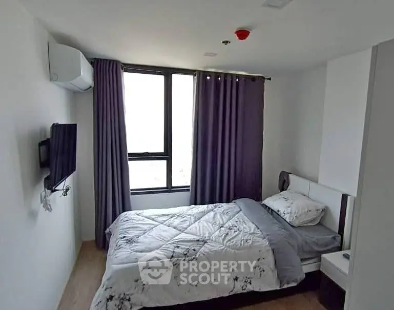 Modern bedroom with large window and stylish decor in a contemporary apartment.