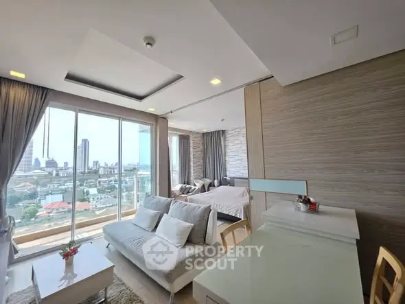 Modern open-plan living room with city view, featuring stylish decor and natural light.
