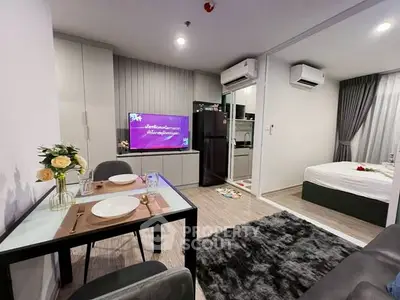 Modern open-plan living room with dining area and bedroom, featuring sleek decor and cozy ambiance.